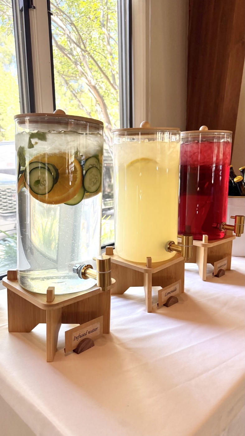 Beverage station with glass dispensers of infused water, lemonade and cranberry juice on bamboo stands