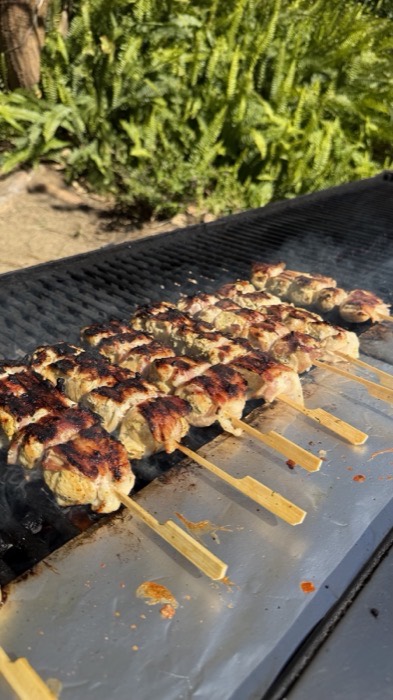 Bacon-wrapped chicken skewers cooking on the grill