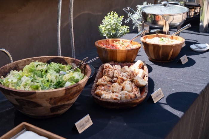 Full catering spread in labelled wooden bowls
