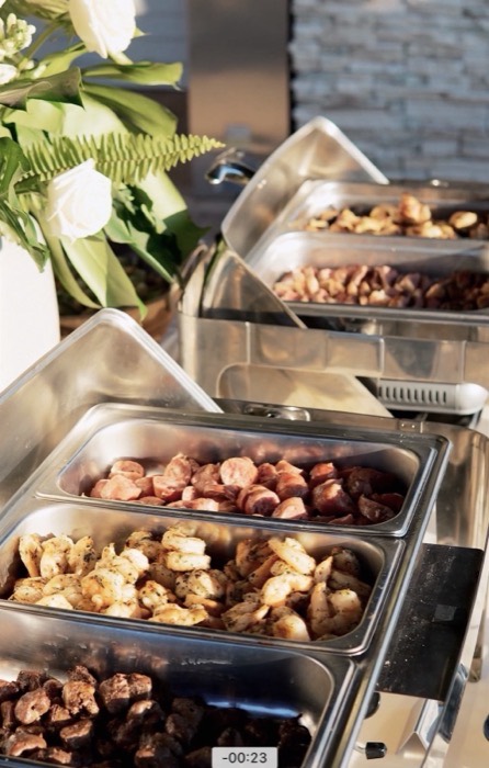 Chafing trays filled with grilled meats on a catering service line