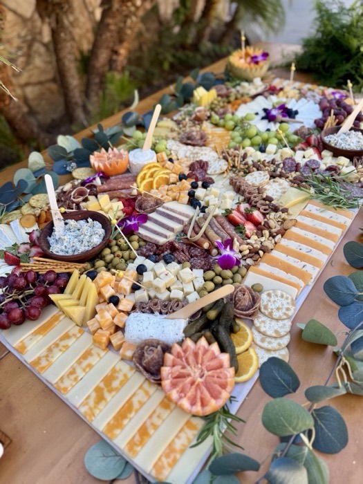 Large charcuterie grazing board with meats, cheeses, fruit and flowers