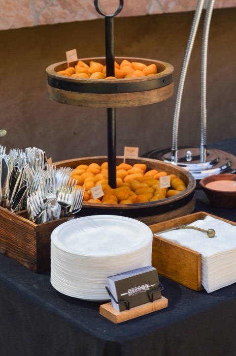 Coxinhas on a tiered wooden stand beside plates and cutlery