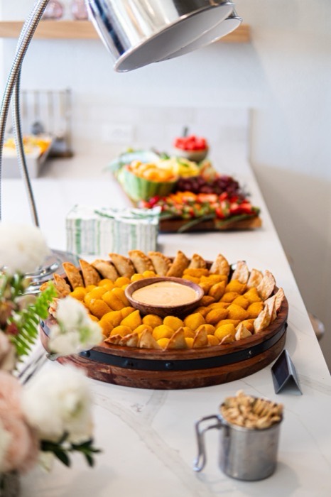 Wooden platter of Brazilian coxinhas and pastéis with a bowl of dipping sauce
