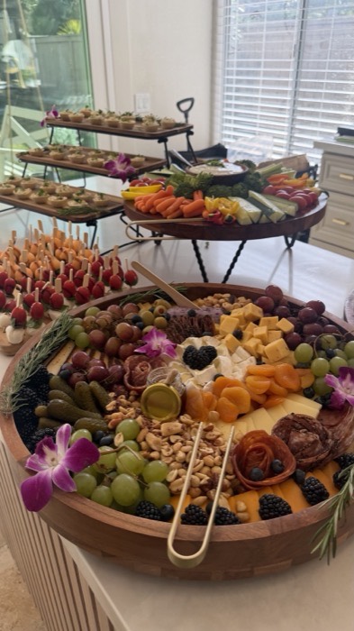 Tiered wooden stands holding desserts and appetisers with flowers