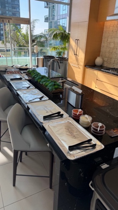 Catering trays, salads and plates laid out on a kitchen island for a drop-off order
