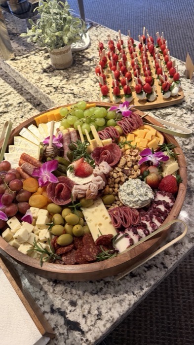 Large grazing board with cured meats, cheeses, fruit and flowers