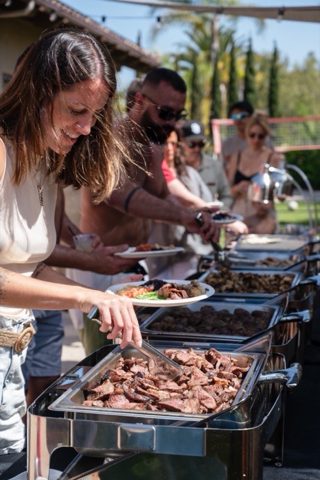 Guests being served grilled meats from the chafing line