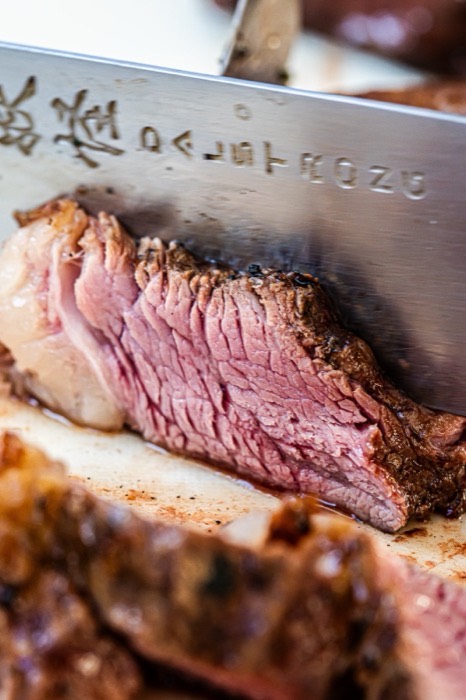Sliced picanha showing a pink medium-rare centre on a carving board