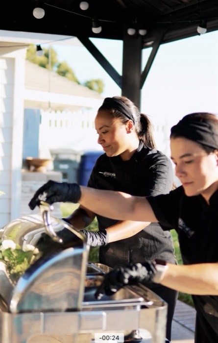Two Stick'n'Bite team members plating food at an outdoor event
