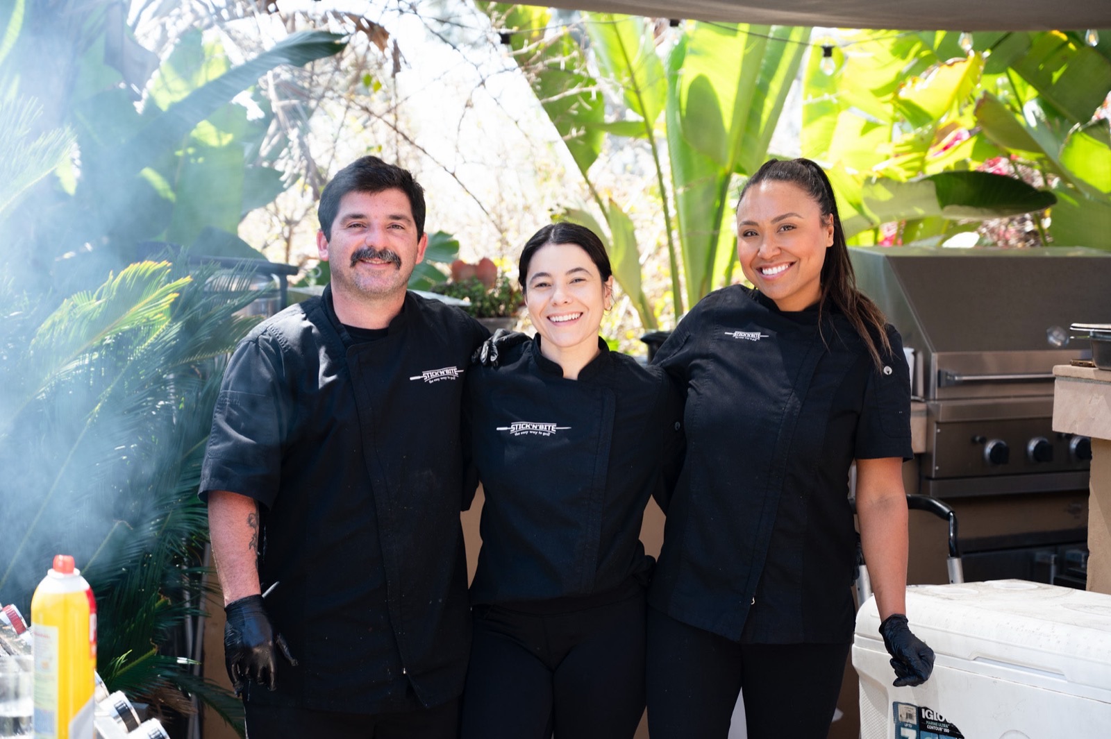 The Stick'n'Bite team in branded chef coats at the grill during a San Diego event